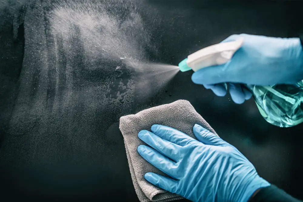 wearing blue rubber gloves cleans a surface