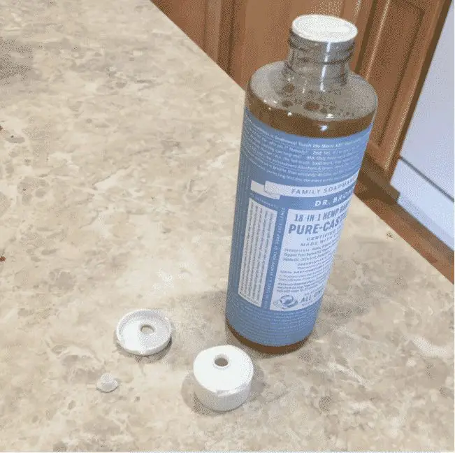 Broken bottle of Dr. Bronner's castile soap on counter
