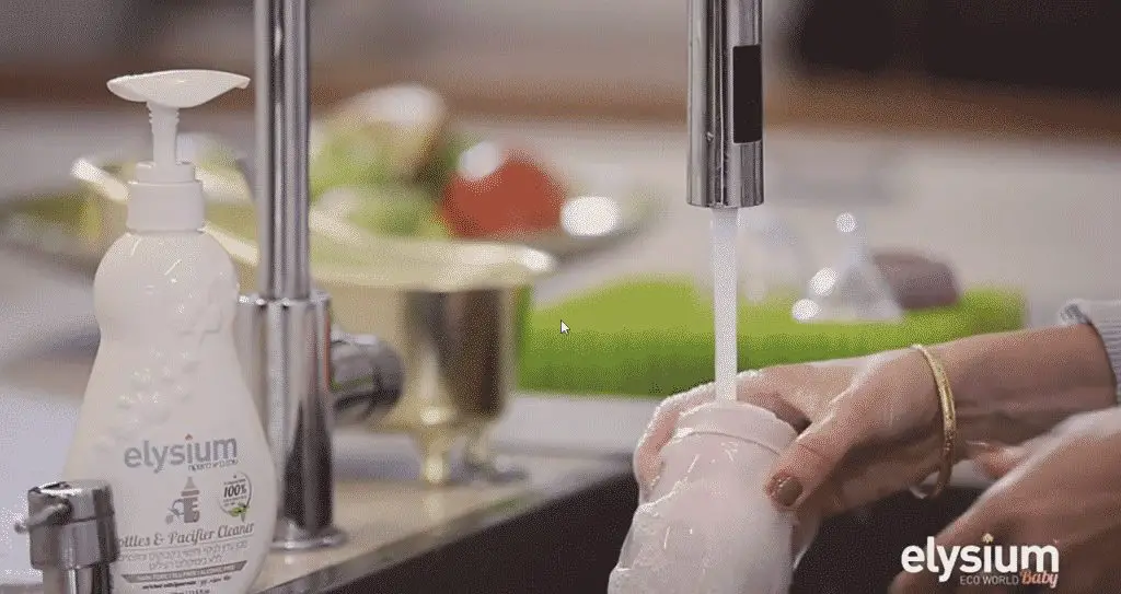 Woman washing a baby bottle in a sink