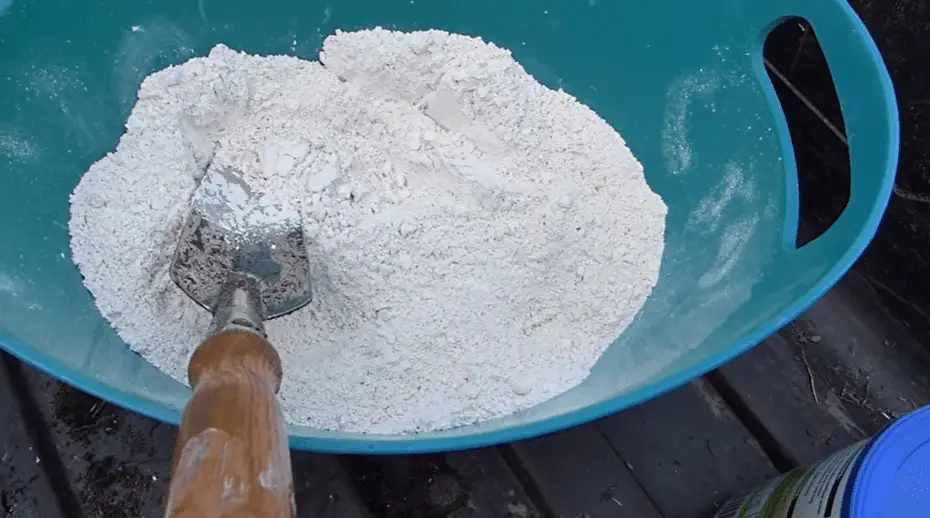 Blue bucket filled with white powder and a shovel on a table