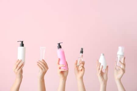 Female,Hands,With,Different,Cosmetic,Products,In,Bottles,On,Color