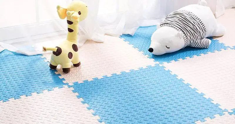 Blue and white puzzle mat with stuffed giraffe and polar bear.