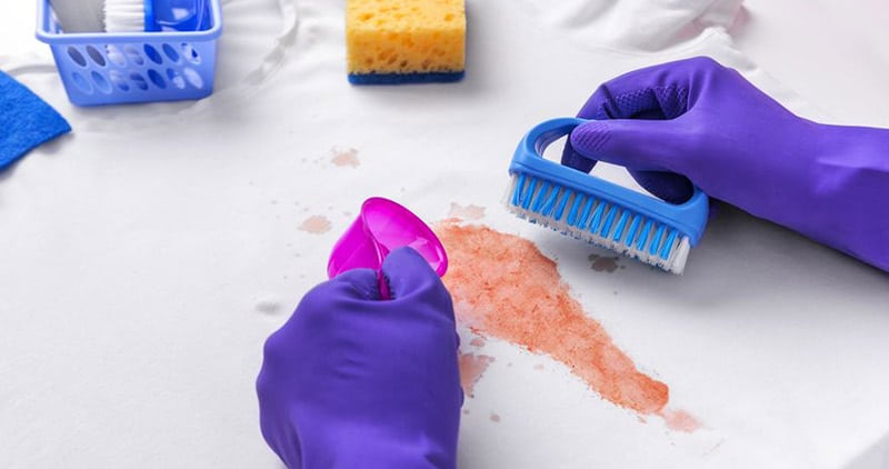 Person cleaning a stain with a brush and spoon