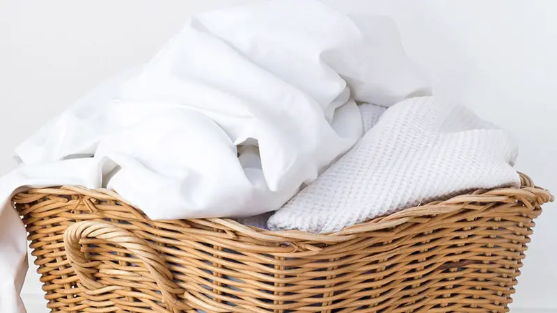 Wicker laundry basket overflowing with white clothes