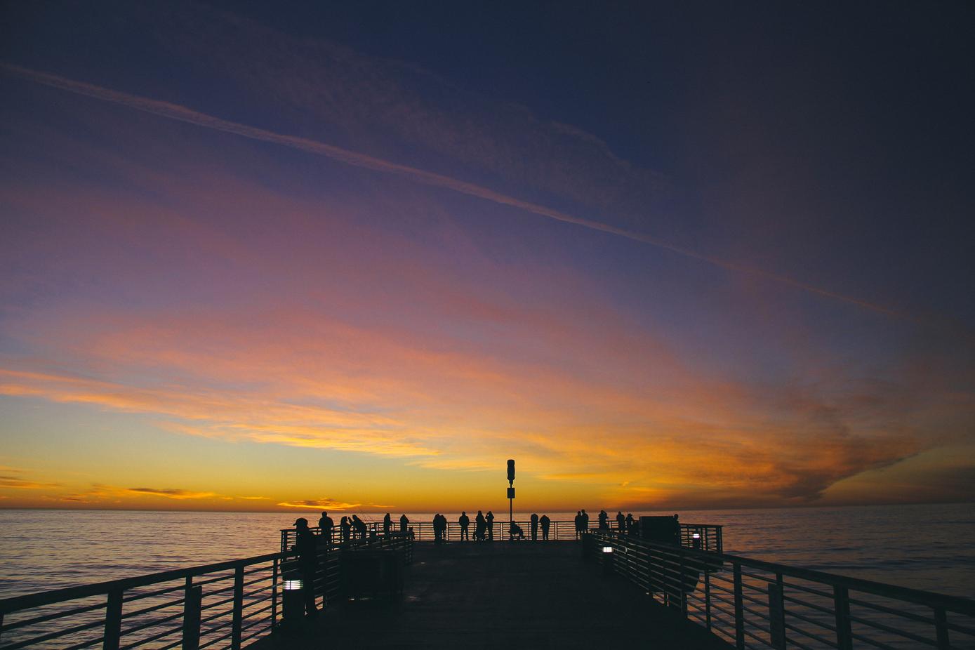 Group of people on a pier at sunset.