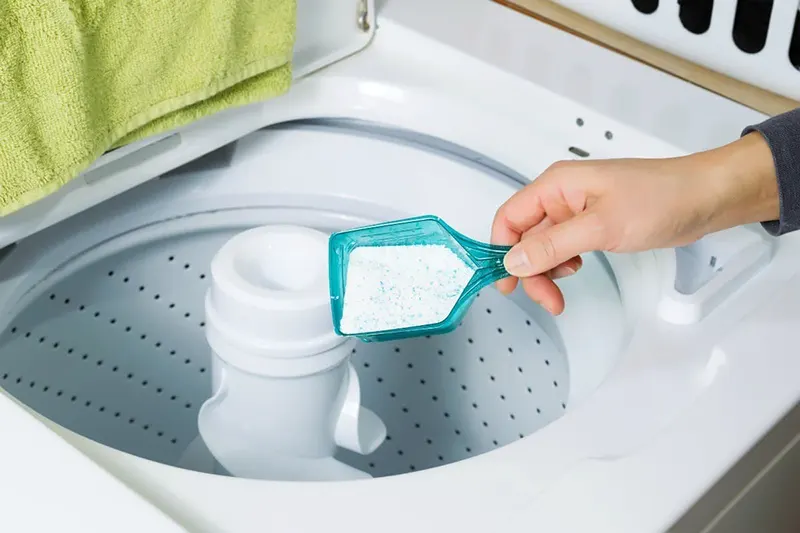 Person pours detergent into washer.