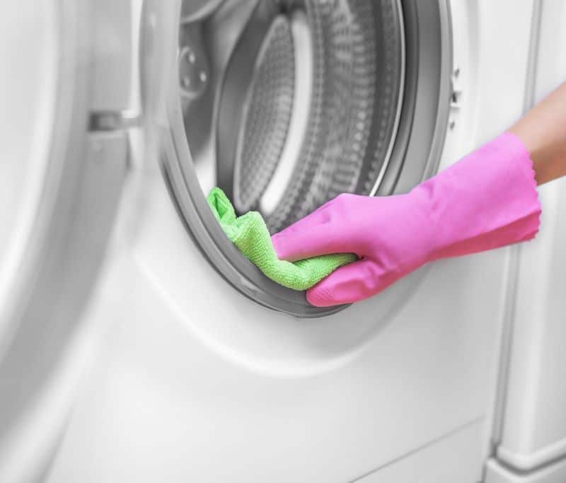 Person in pink gloves cleans washer