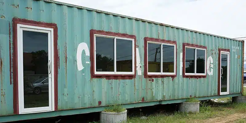 Green shipping container with three windows and two doors