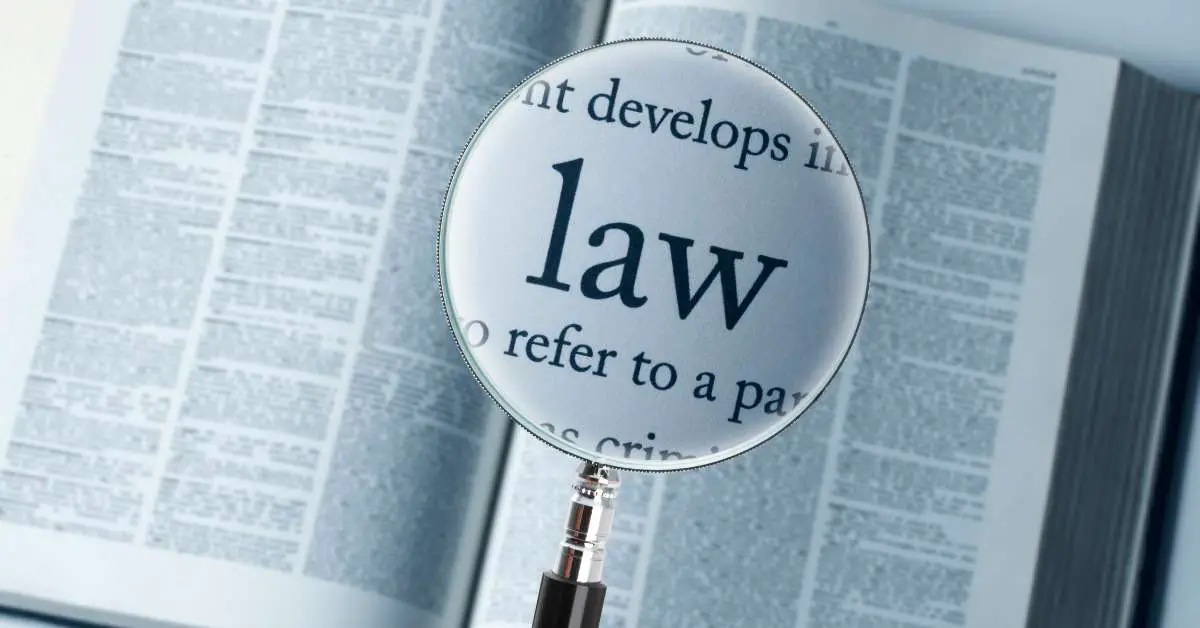 a magnifying glass on top of an open book zooming in on the word "law"