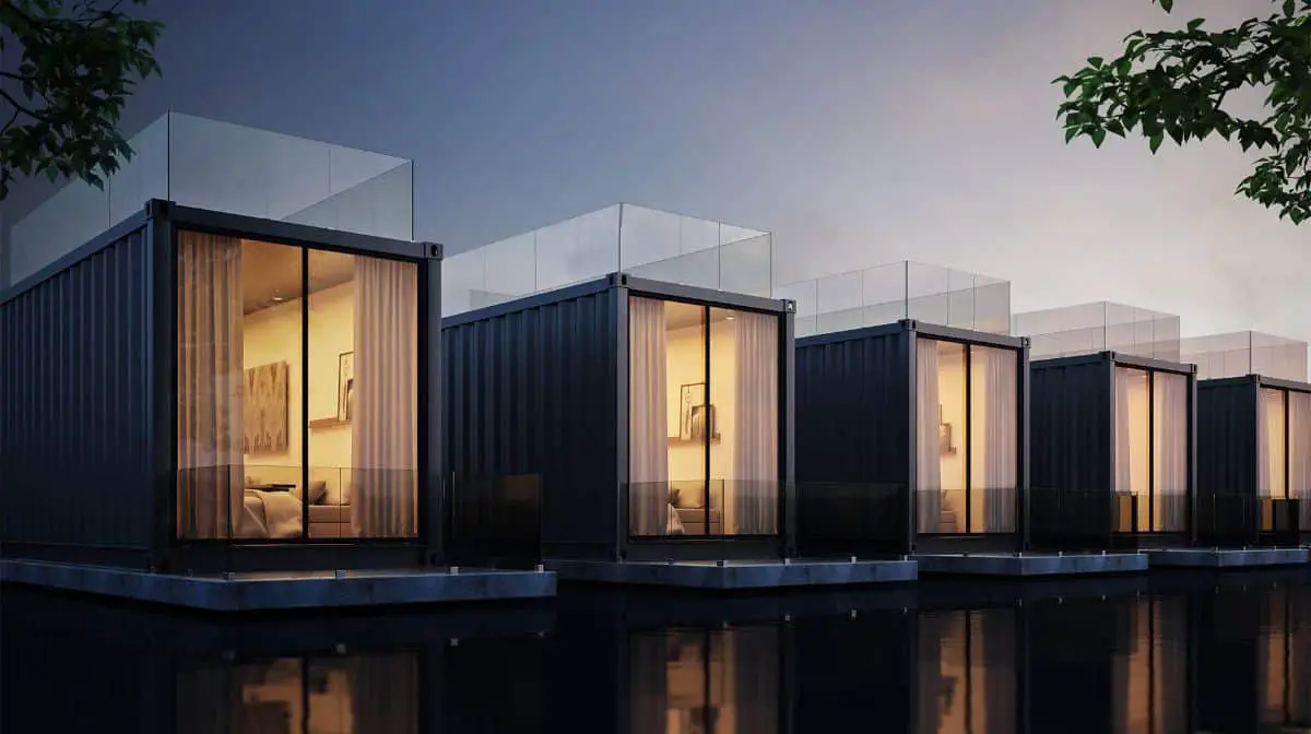 A line of single shipping container homes with lights open inside.