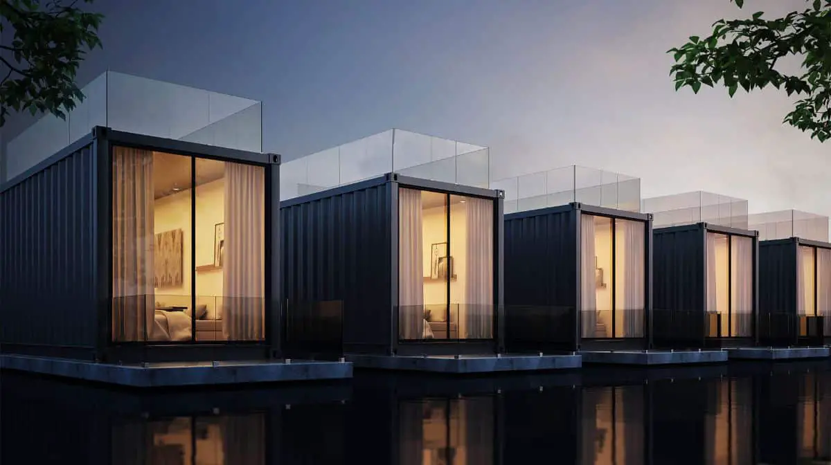 A line of single shipping container homes with lights open inside. 