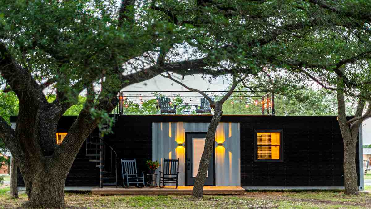 A modern shipping container home with black exterior.