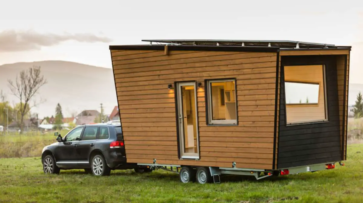 A tiny home being transported by a car.