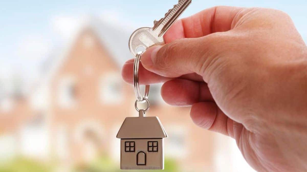 A hand holding a key to a new house.