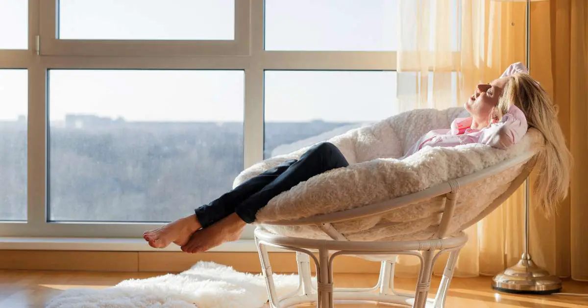 a woman relaxing on her chair beside a big window in her house