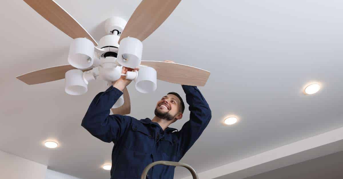 a man fixing a ceiling fan with lights