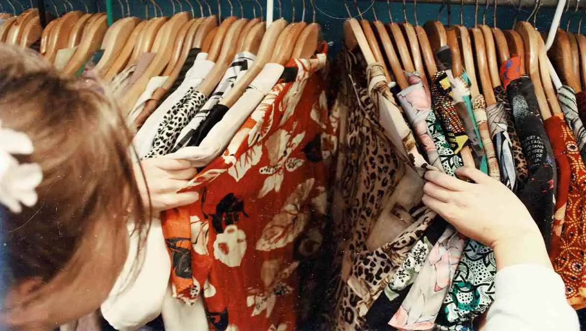 A woman scanning colorful clothes in a store rack. 