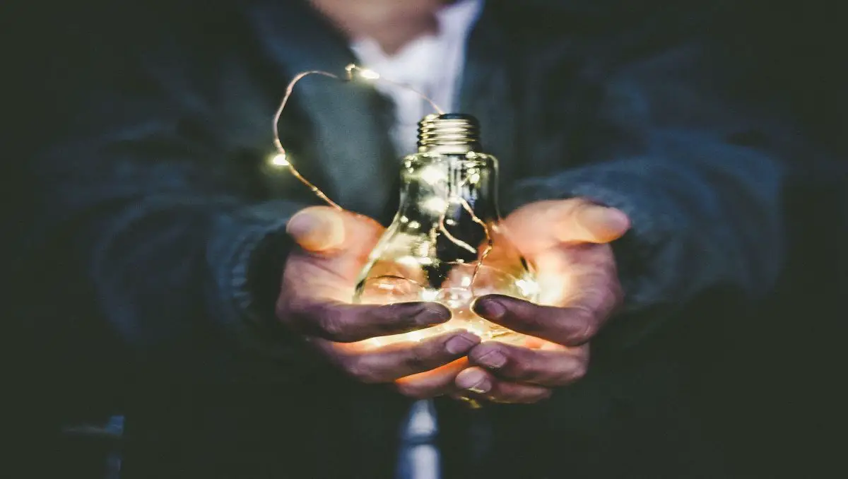 A man holding a light bulb with both his hands.