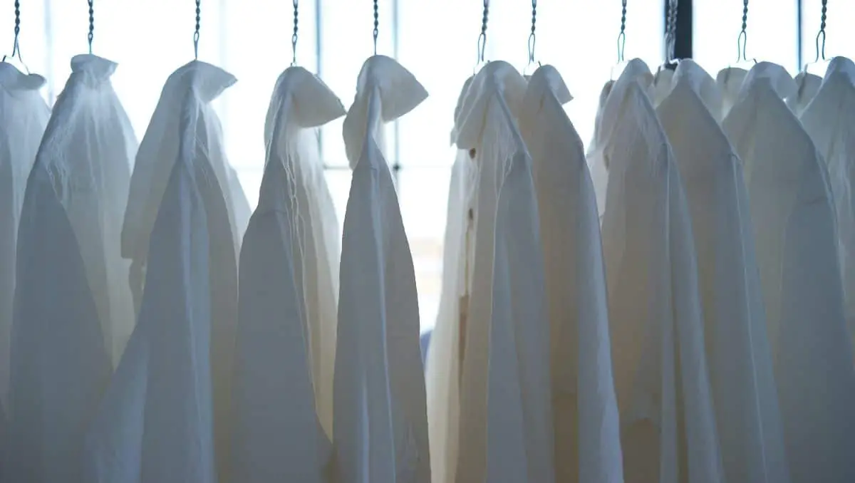 A line of white polos being hanged and air-dried. 