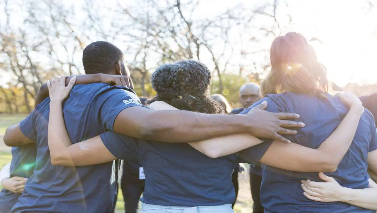 Men and women of different races holding hand in hand forming a circle.