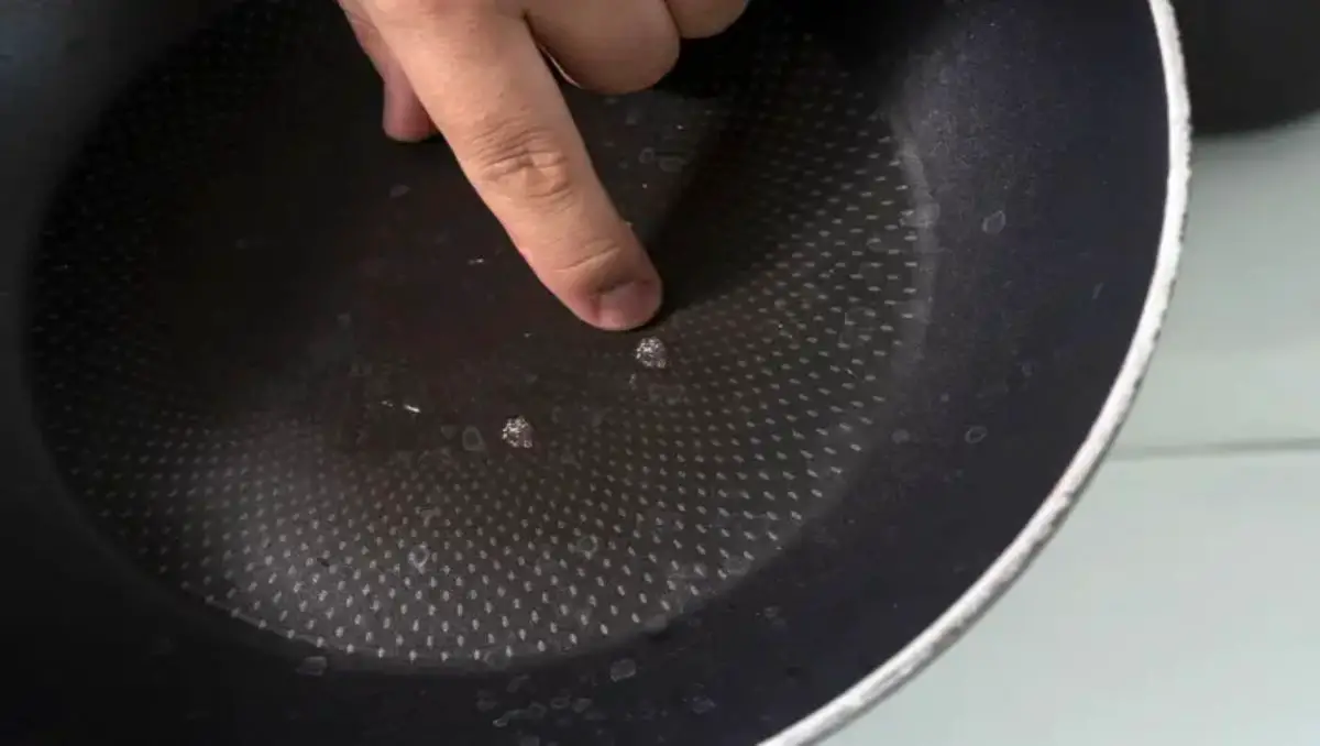 A finger pointing on the scratches on teflon nonstick pan. 