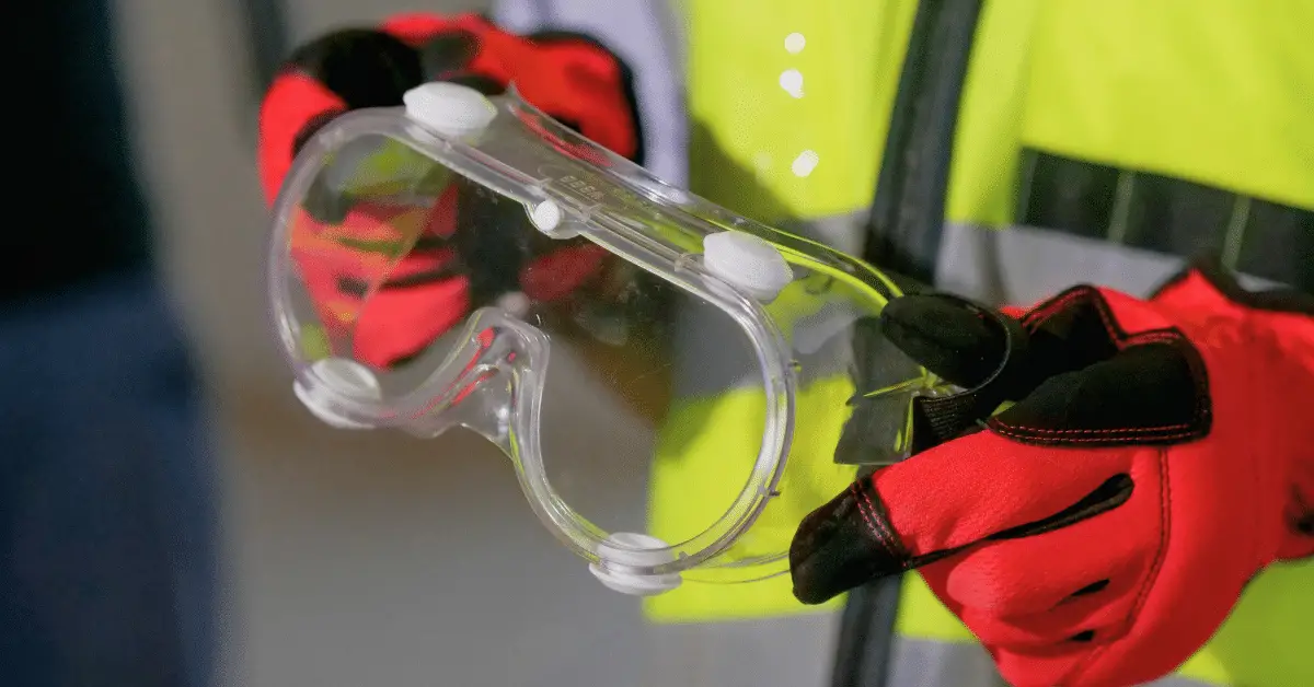 a person wearing protective equipment and holding safety goggles