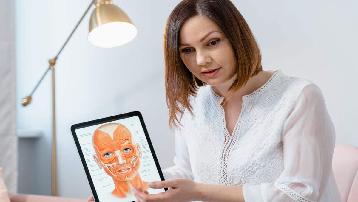 A dermatologist holding an iPad illustrating the parts of the facial skin.