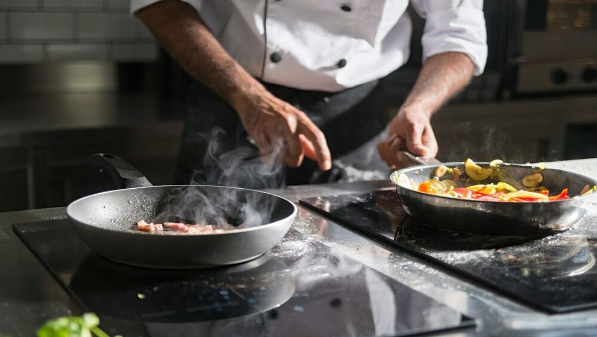 A chef cooking in the kitchen using two teflon pans.