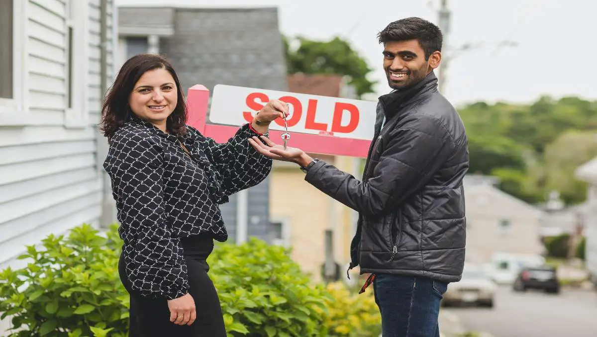 A woman handing the new house keys to the man.