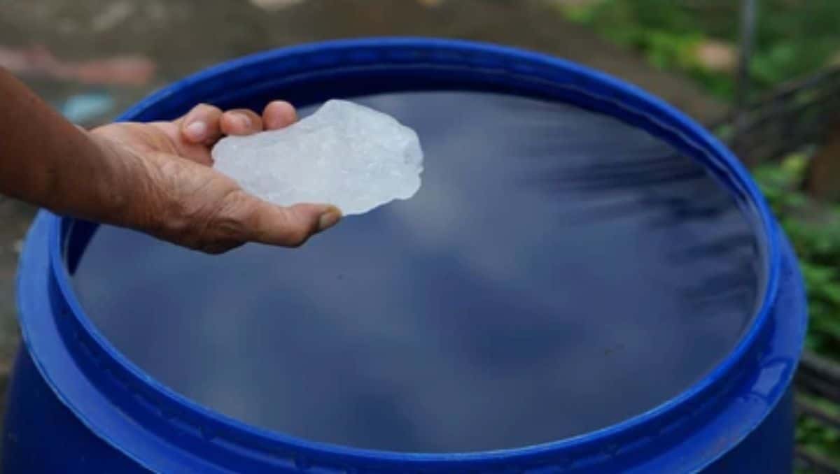 A hand about to dip an alum stone in a container full of water.