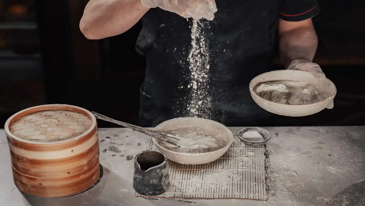 A baker pouring baking soda on the bowl.