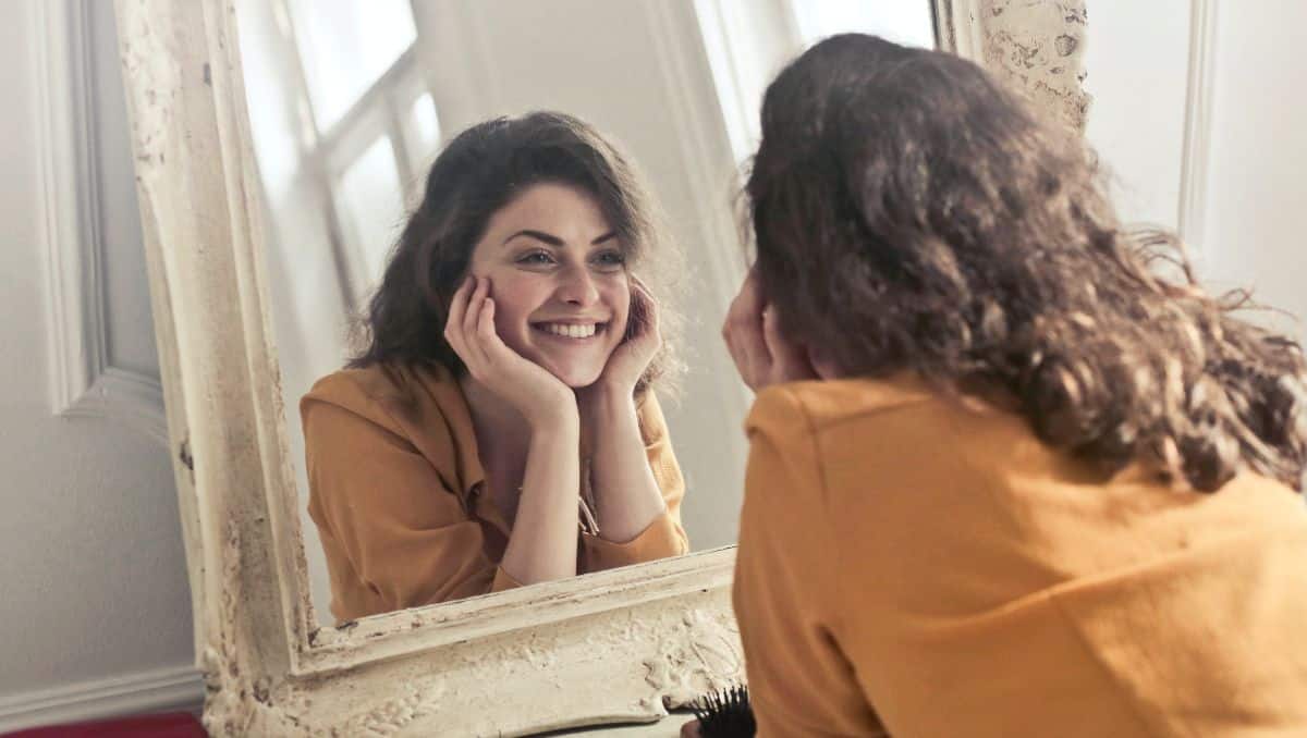 A girl smiling at her reflection in the mirror.