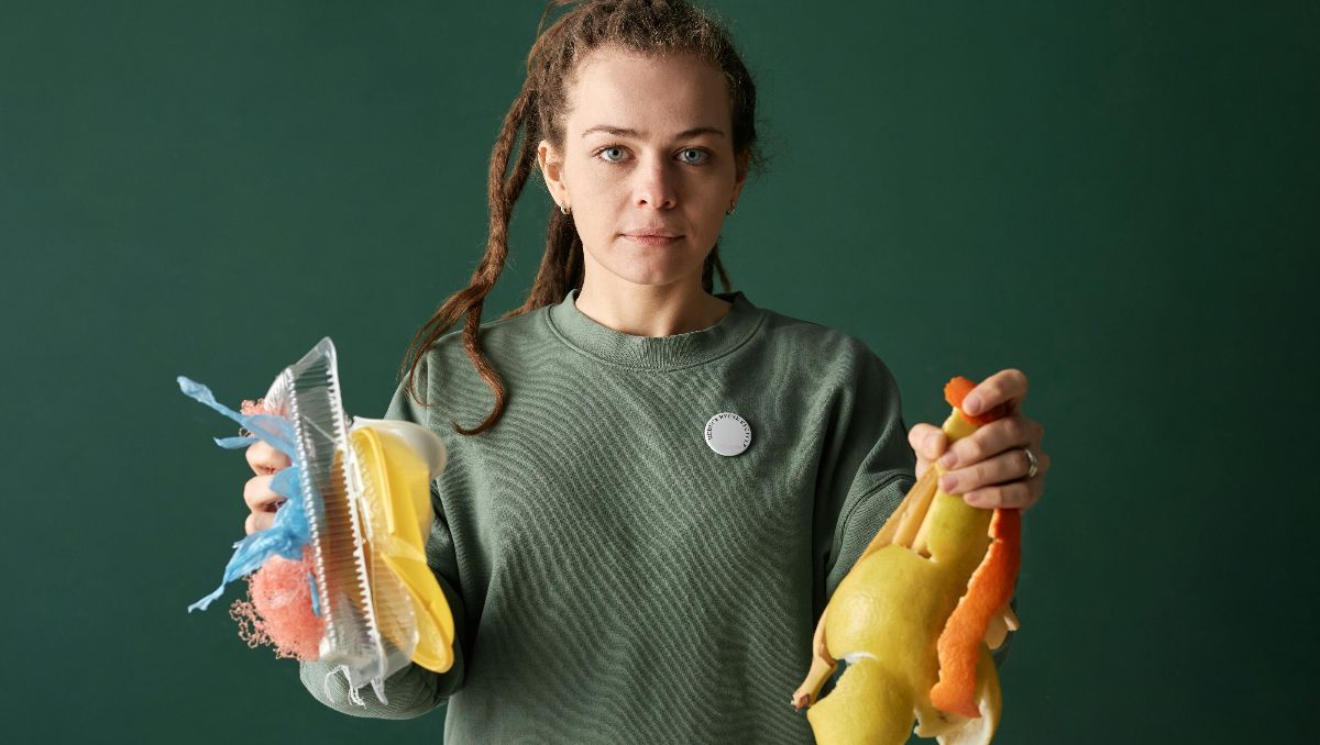 A girl holding plastic and fruit peel wastes.