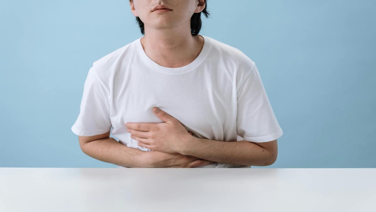 A man holding his stomach indicating stomach pain.